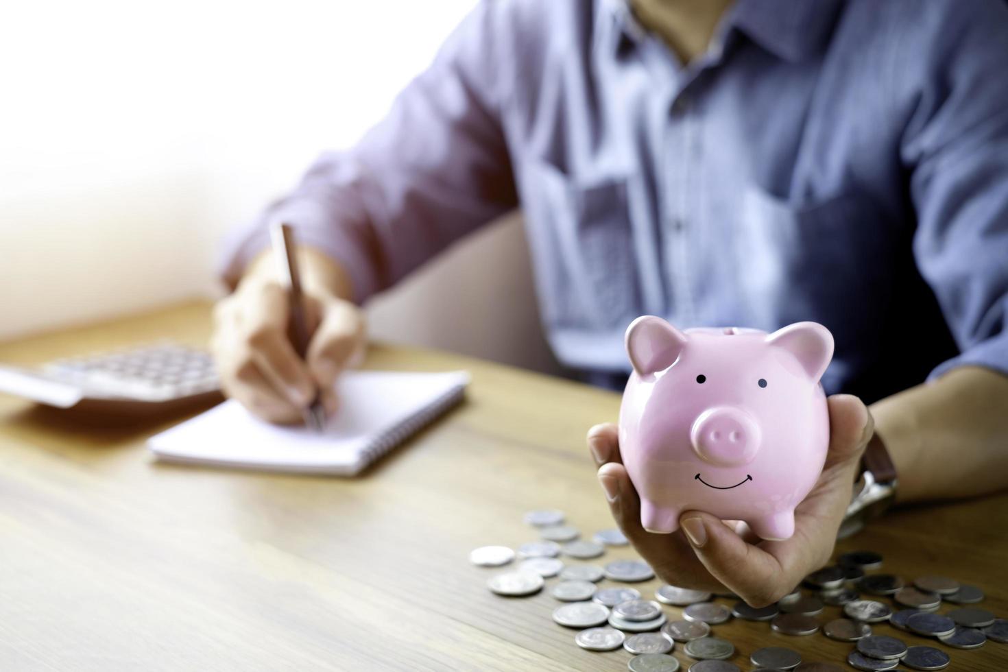 Bild des rosafarbenen Sparschweins auf der Hand mit Münzen auf dem Tisch, um Geld zu sparen. planung steigern, geld sparen für zukunftsplan, pensionsfonds. Business Investment-Finance Accounting-Konzept. foto