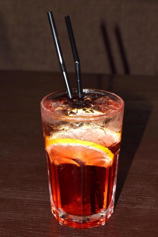 erfrischender cocktail mit strohhalm, eiswürfeln und einer zitronenscheibe foto