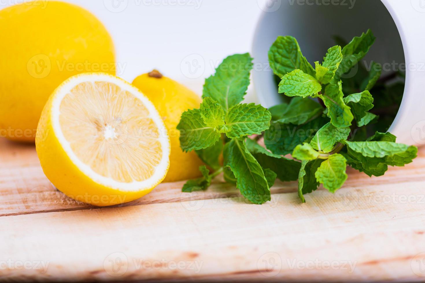 Zitrone und Minze auf einem Holztisch platziert foto