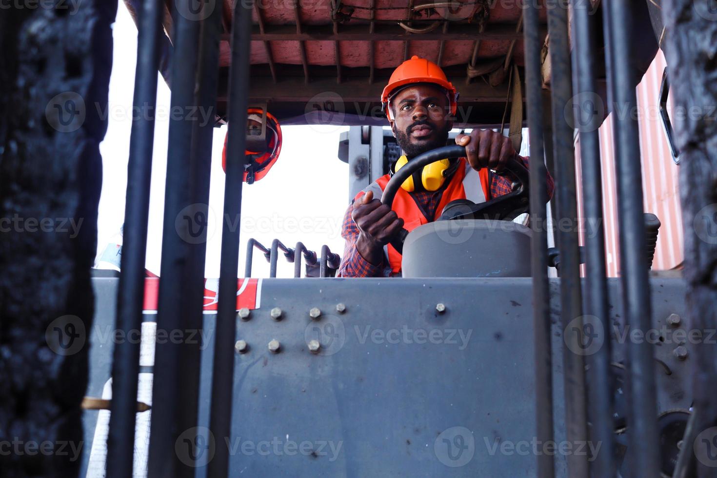 industriearbeiter mann trägt sicherheitsleuchtweste und helm, der gabelstaplerwagen in der werksfabrikindustrie fährt, afroamerikanischer ingenieurmann, der auf dem hof der logistischen versandfrachtcontainer arbeitet. foto