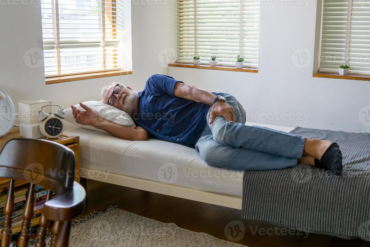 Ein älterer Mann mit grauem Haar schläft tagsüber im Schlafzimmer, um sich zu entspannen. foto