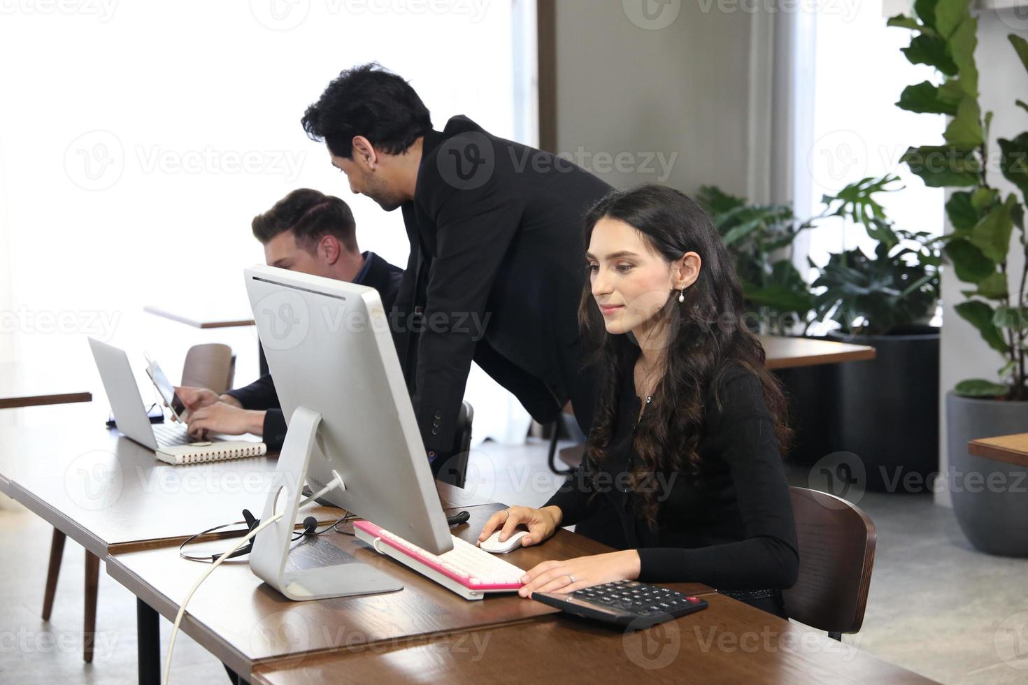 Geschäftsleute. gruppe junger selbstbewusster geschäftsleute, die daten mithilfe des computer analysieren, während sie zeit im büro verbringen foto