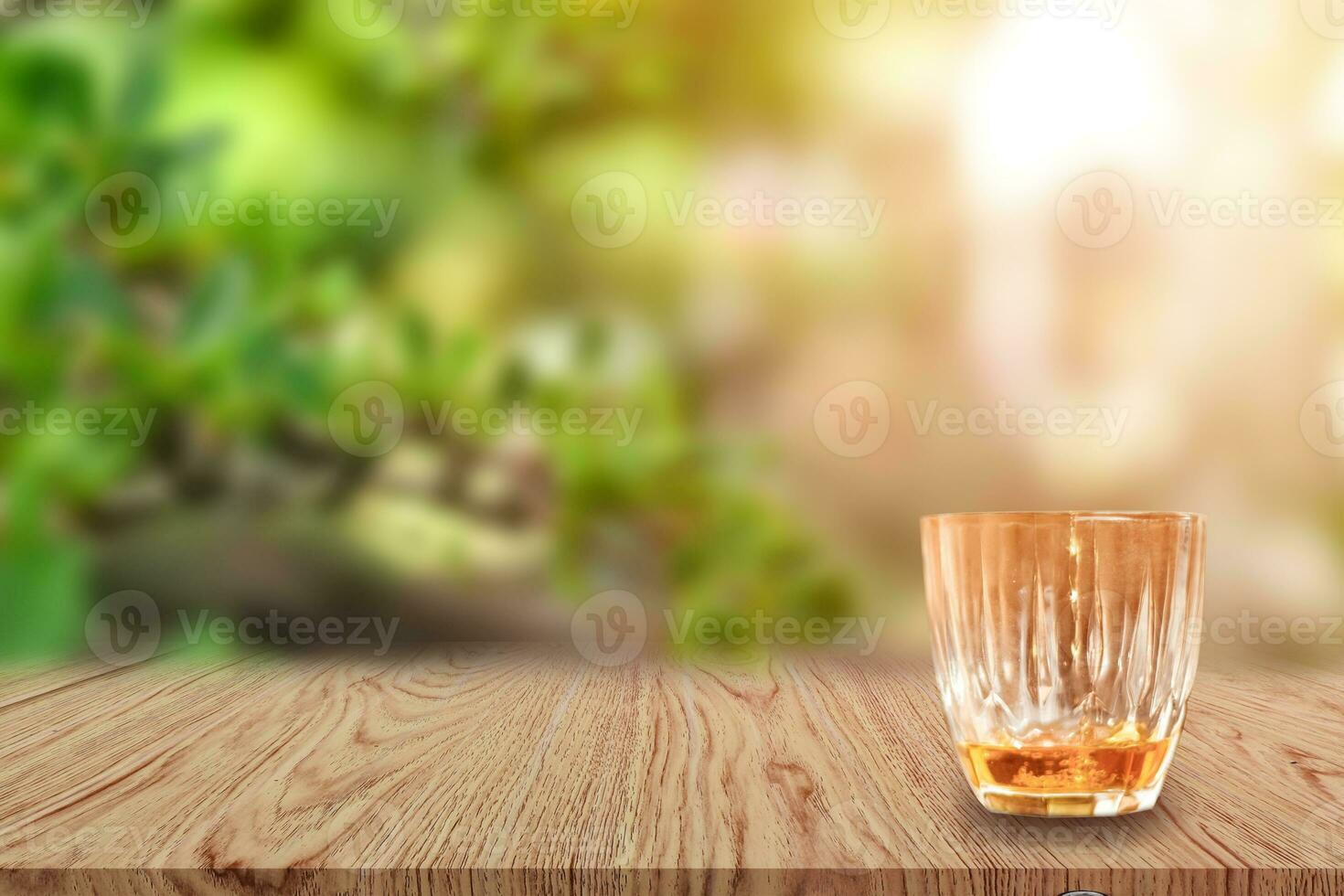 ein glas whisky auf holztisch und leicht verschwommenem naturhintergrund. foto