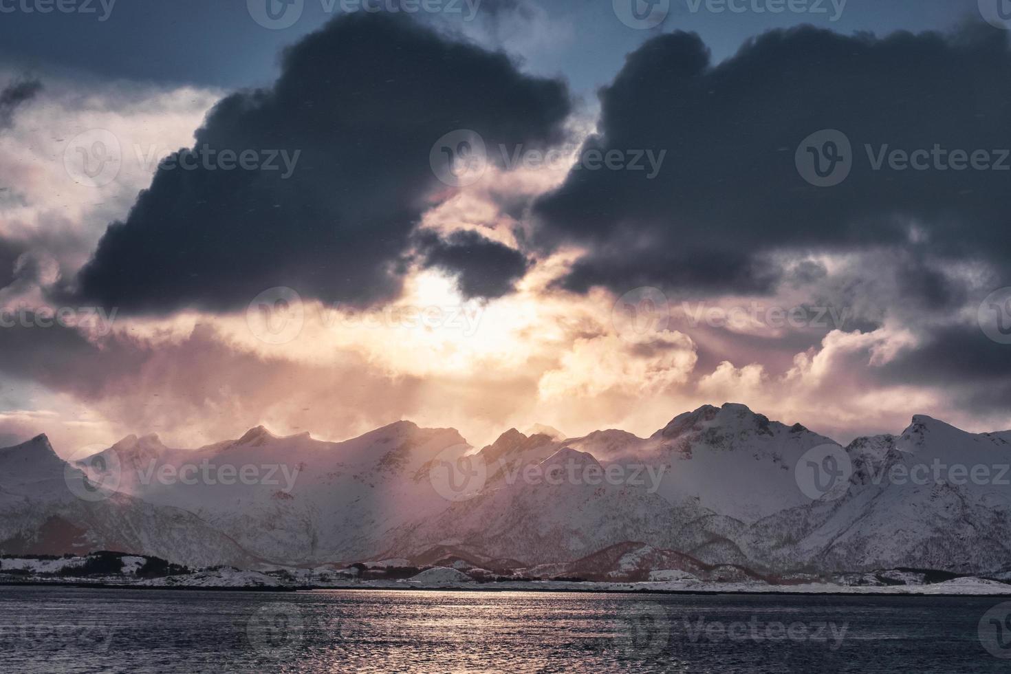 Sonnenuntergang bei bewölktem Himmel auf schneebedeckter Bergkette auf der Insel Senja foto