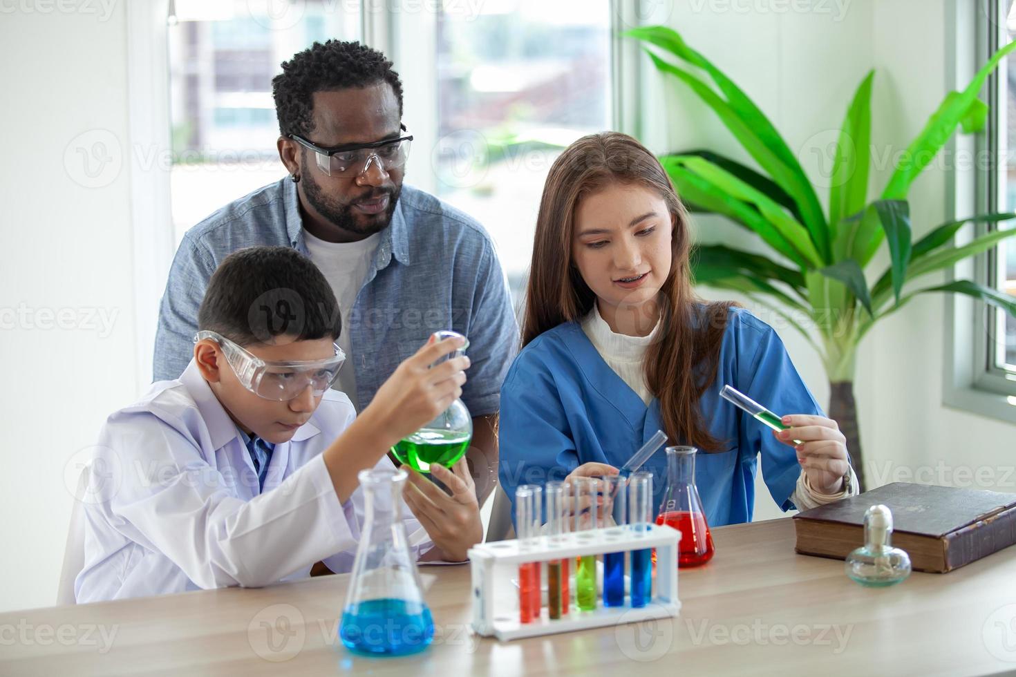 Studenten mischen Chemikalien in Bechergläsern. begeisterter lehrer erklärt kindern chemie, chemiestudent zeigt dem naturwissenschaftsunterricht ein neues experiment foto