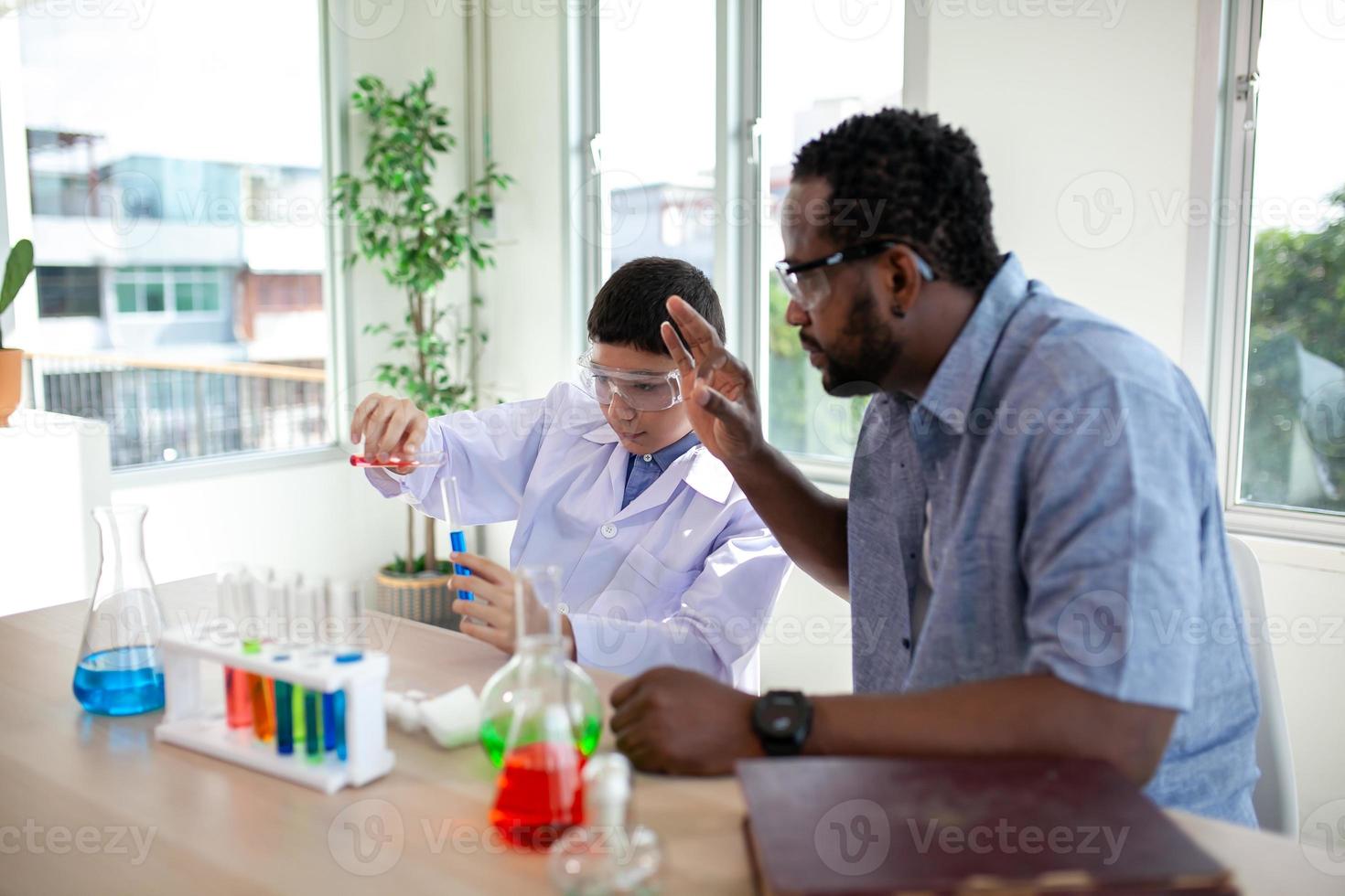 Studenten mischen Chemikalien in Bechergläsern. begeisterter lehrer erklärt kindern chemie, chemiestudent zeigt dem naturwissenschaftsunterricht ein neues experiment foto