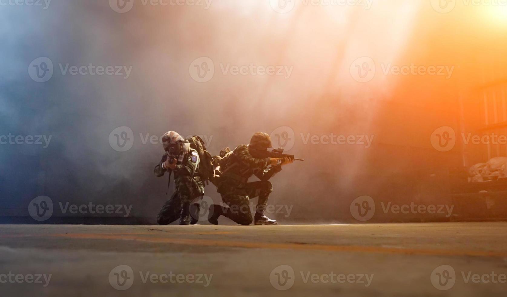 Silhouetten von Armeesoldaten im Nebel vor Sonnenuntergang, Marinesoldaten im Einsatz, Feuer und Rauch umgeben, mit Sturmgewehr und Maschinengewehr schießen, Feind angreifen foto