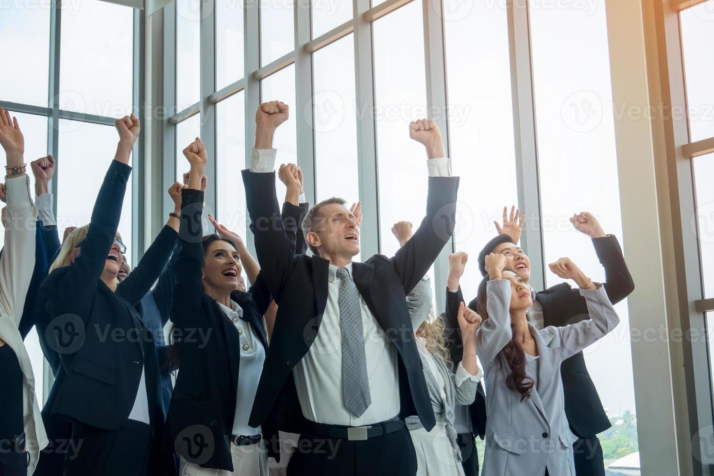 erfolgreiche geschäftsleute, die zusammenstehen, erweitern sich und zeigen eine starke beziehung der arbeitnehmergemeinschaft. ein team von geschäftsleuten und geschäftsfrauen, die eine starke gruppenteamarbeit im modernen büro zum ausdruck bringen. foto