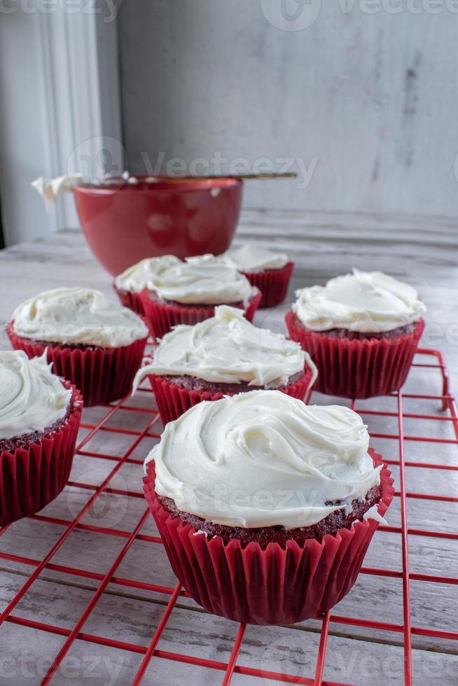 Red Velvet Cupcakes mit weißem Zuckerguss auf rotem Drahtgestell foto