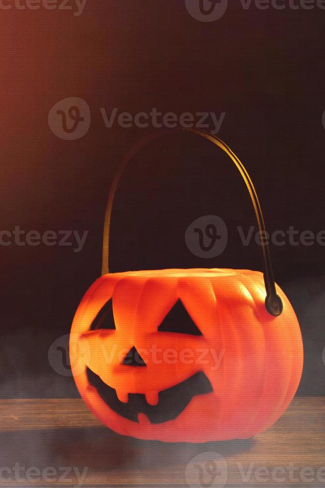 halloween-konzept - orangefarbene plastikkürbislaterne auf einem dunklen holztisch mit verschwommenem funkelndem licht im hintergrund, süßes oder saures, nahaufnahme. foto