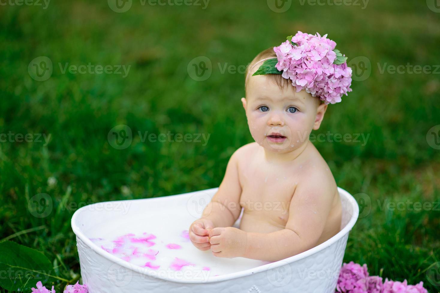 kleines Mädchen badet in einem Milchbad im Park. Das Mädchen hat Spaß im Sommer. foto