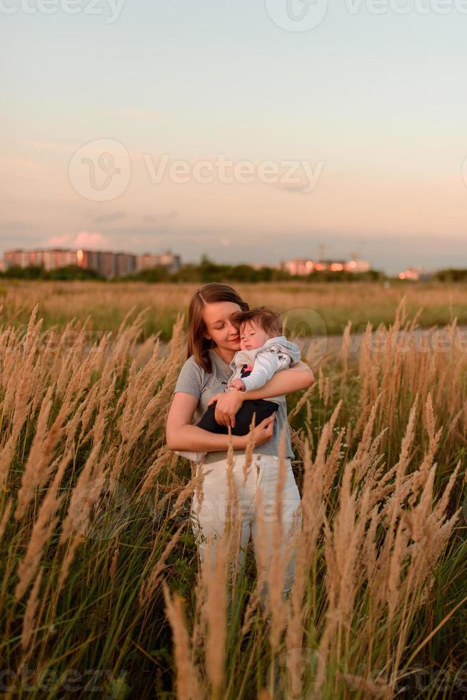 Eine Mutter geht mit ihrer kleinen Tochter im Arm über das Feld. foto