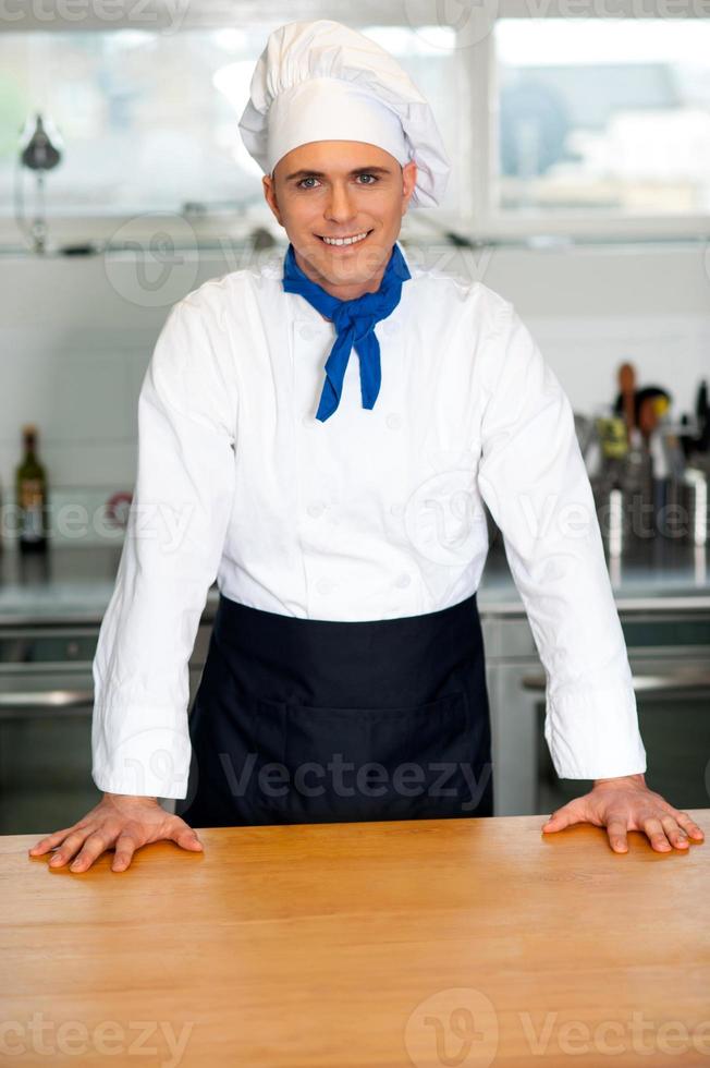 hübscher junger Koch, der in Uniform aufwirft foto