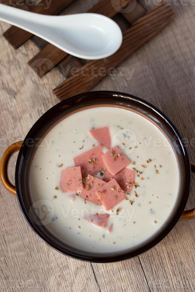 Käsesuppe mit Gemüse und Schinken mit Toast Nahaufnahme auf dem Tisch. horizontal Oregano in braune Schüssel streuen. foto