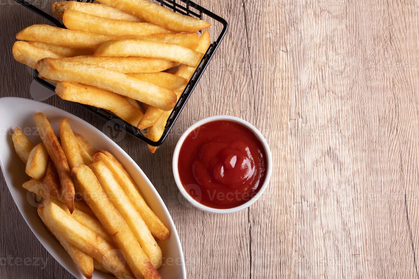 Pommes Frites in einem schwarzen Korb mit Tomatensauce foto