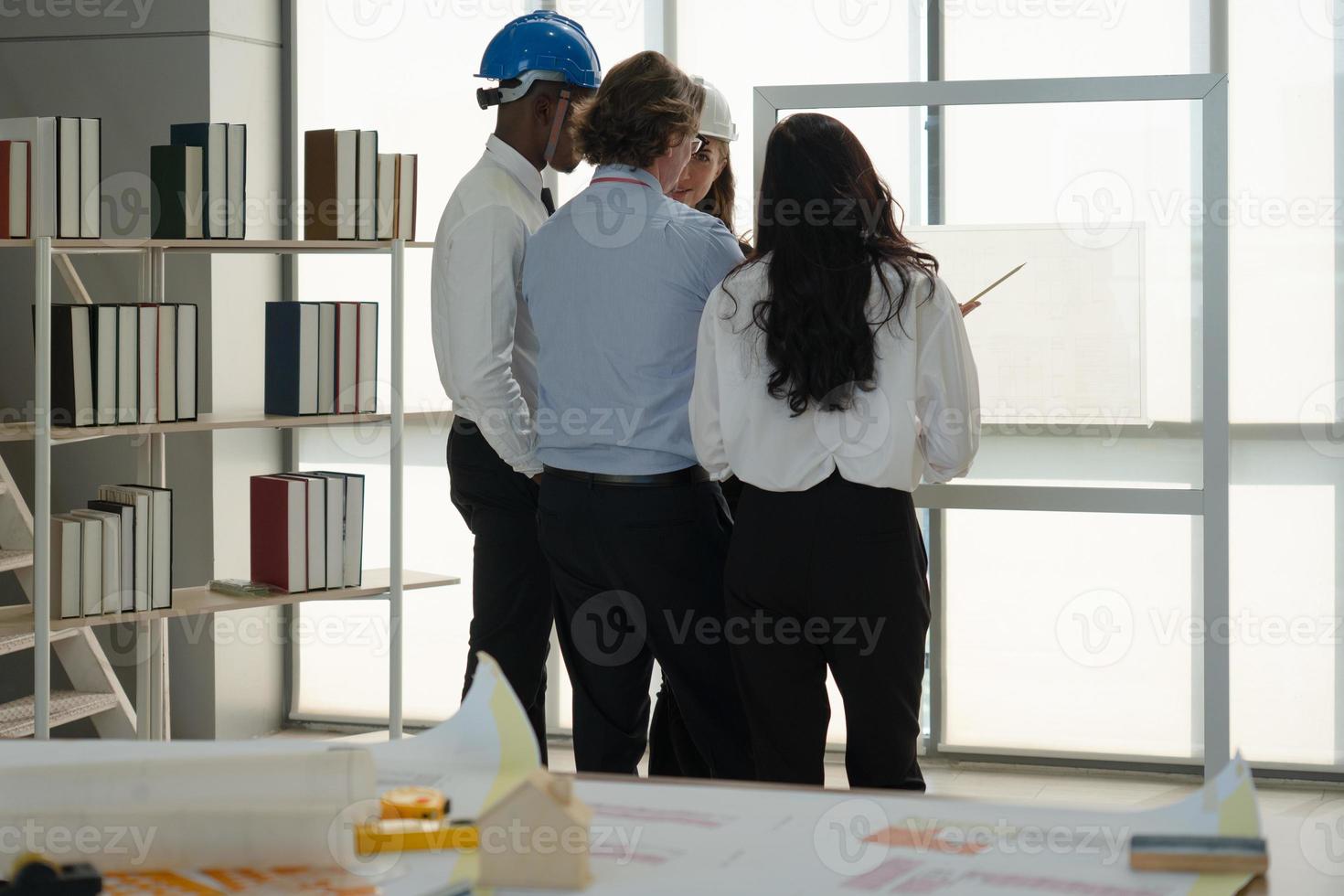 geschäftsleute von bauunternehmen, die pläne im büro betrachten foto