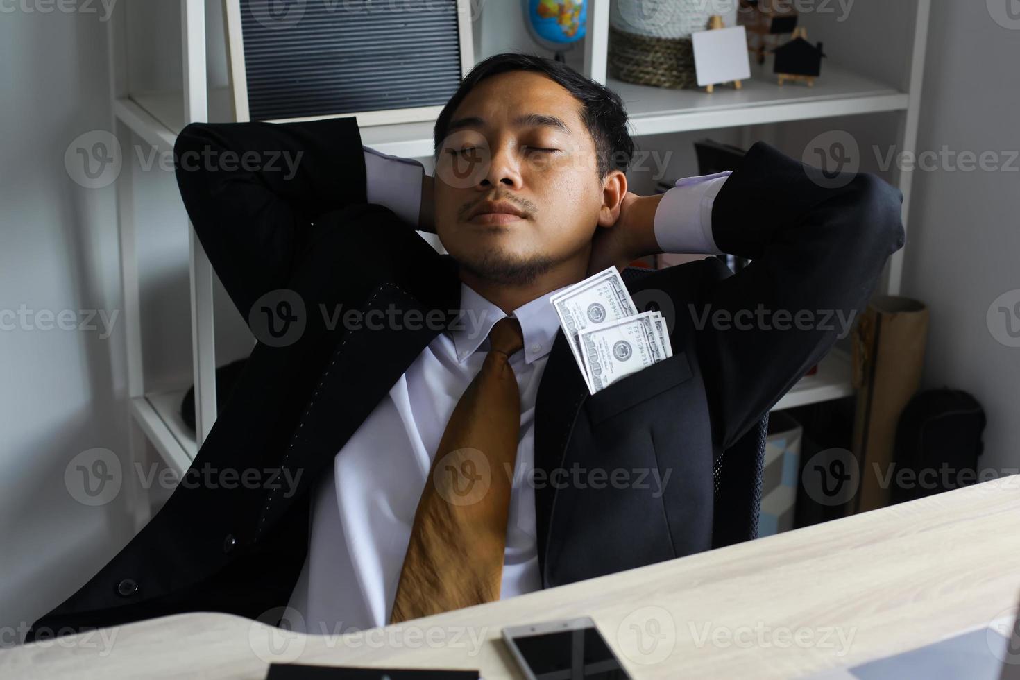 Geschäftsmann, der auf seinem Bürostuhl liegt, nachdem er ein Bestechungs-, Bestechungs- und Korruptionskonzept erhalten hat foto