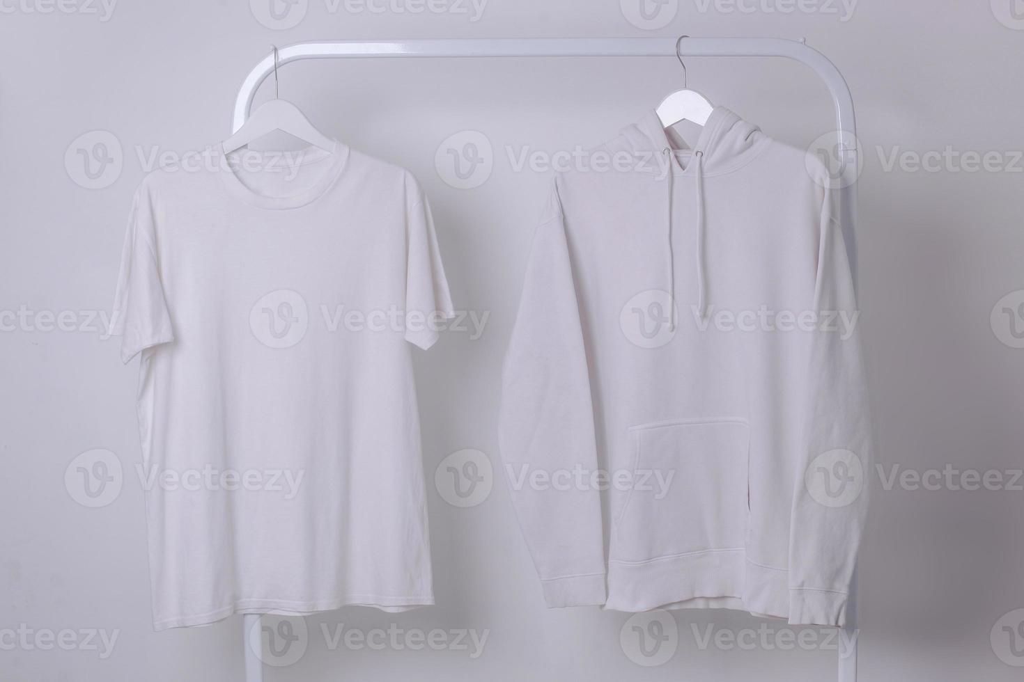 Modell eines weißen Basic-T-Shirts und Hoodies, das an einem Kleiderständer hängt foto