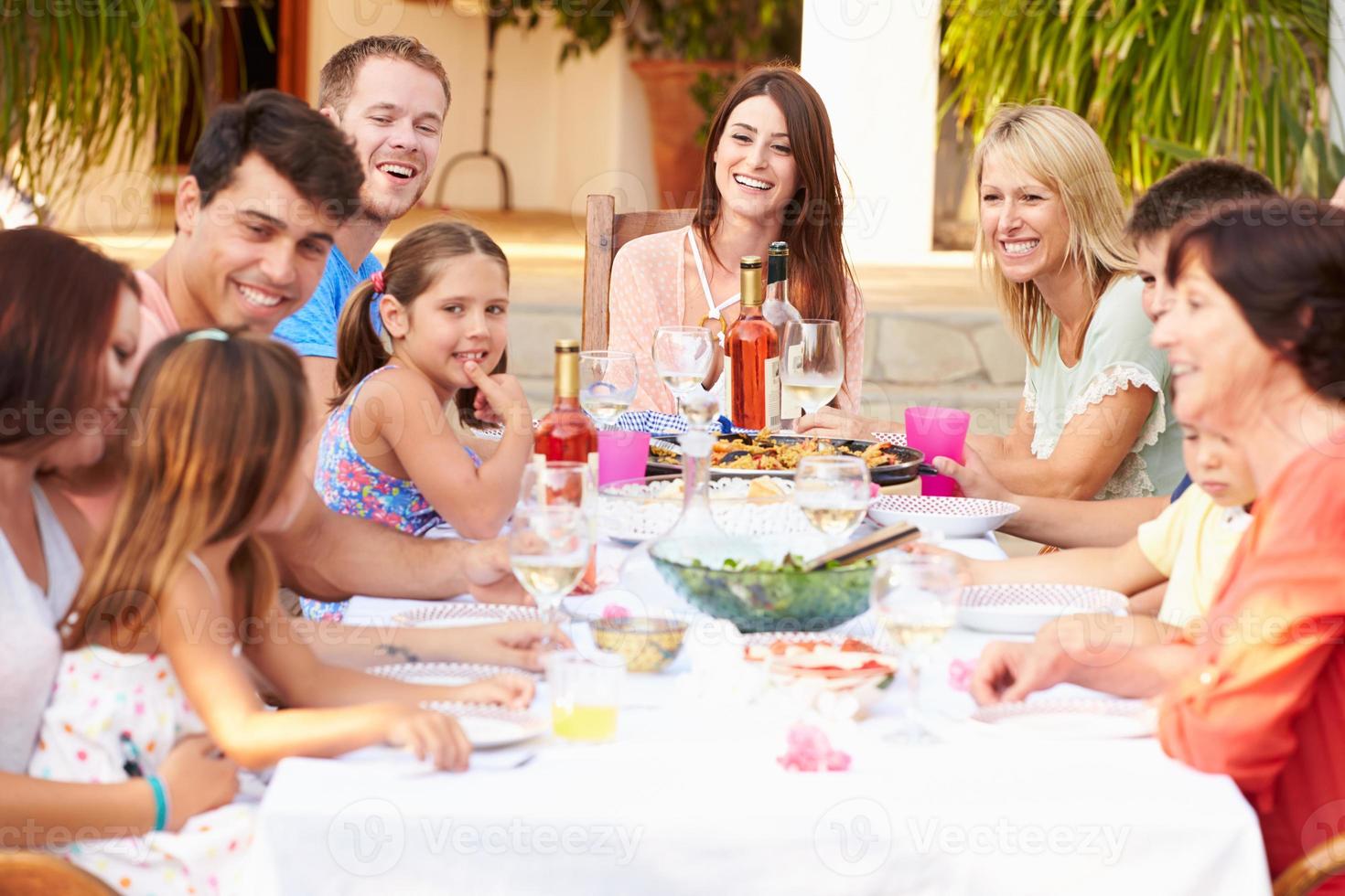 große Familiengruppe, die gemeinsam auf der Terrasse isst foto