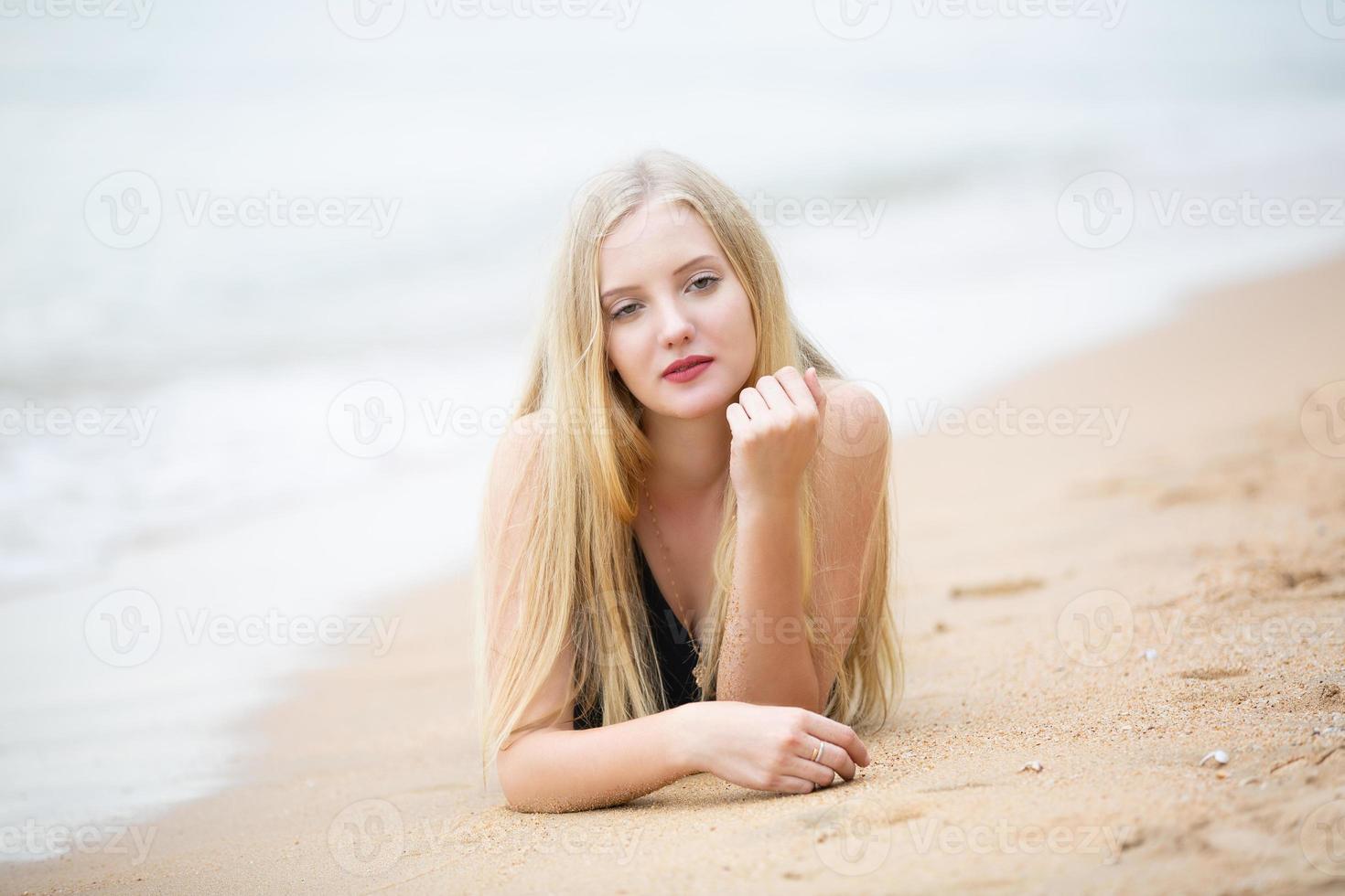 schöne blonde Frau im schwarzen Bikini genießen Sie die Sommerzeit am Strand. foto