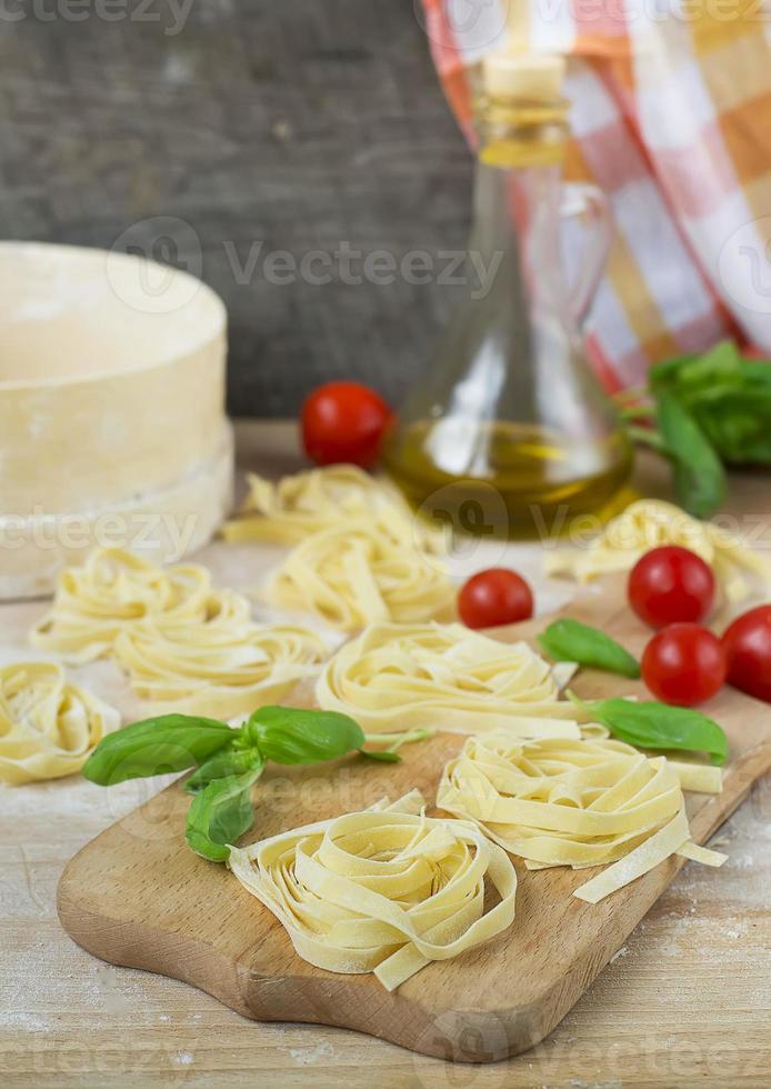 frische hausgemachte Pasta Maschine Pasta, Basilikum, Tomaten auf einem Holz foto