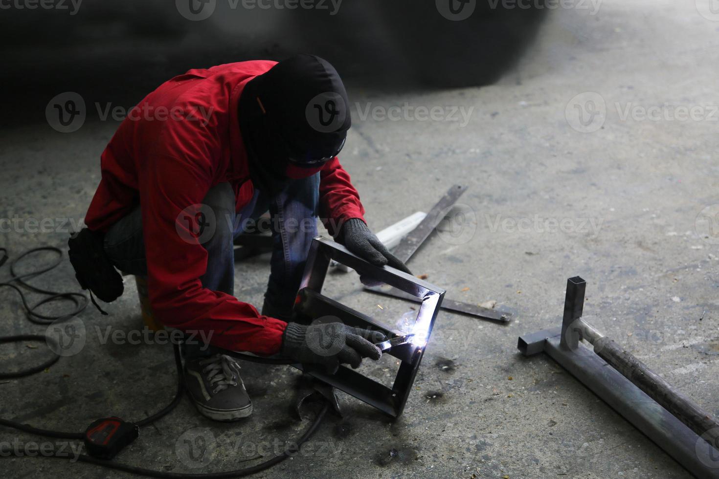 Schweißer verwendet Schleifstein auf Stahl in Fabrik mit Funken, Schweißprozess in der Industriewerkstatt, Hände mit Instrument im Rahmen. foto