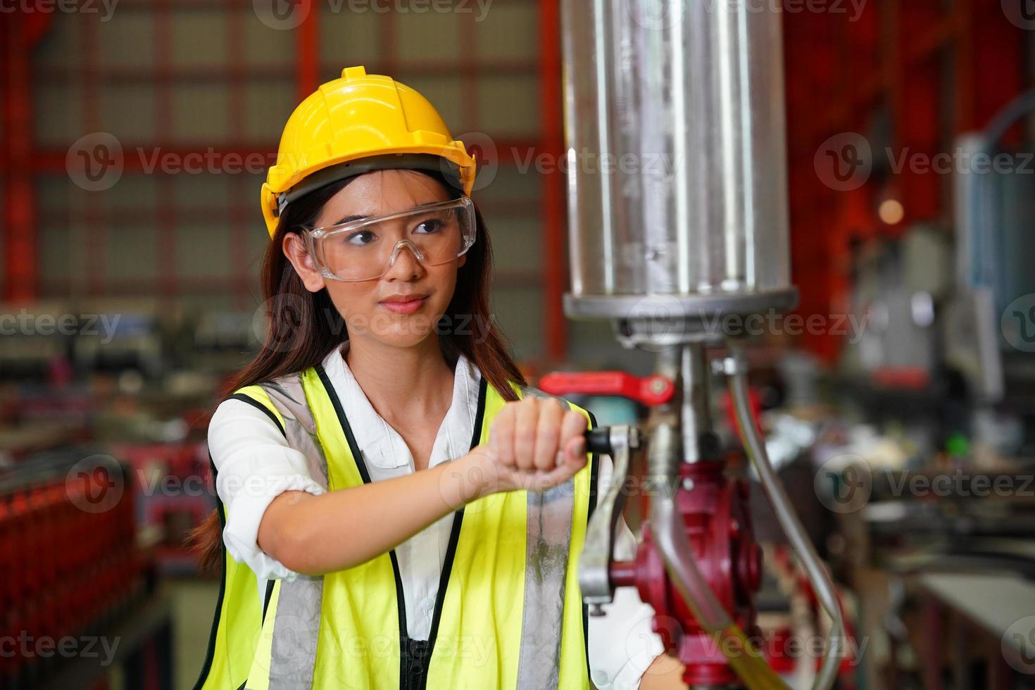 weiblicher Wirtschaftsingenieur, der einen Schutzhelm trägt, während er in einer Schwerindustriefabrik steht. die Wartung von Arbeiten an Industriemaschinen und die Einrichtung des Sicherheitssystems in der Fabrik. foto