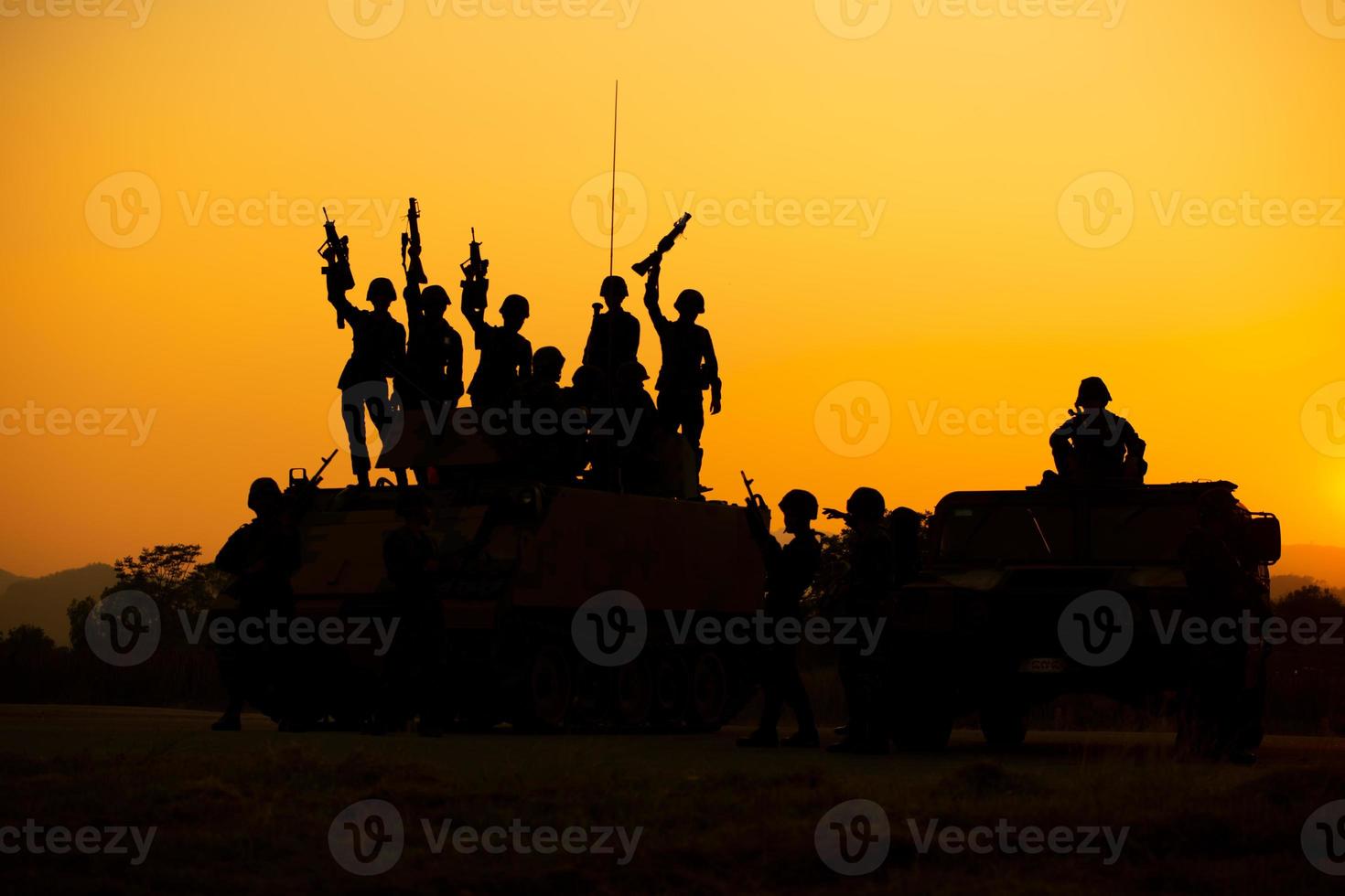 Silhouetten von Armeesoldaten im Nebel vor Sonnenuntergang, Marinesoldaten im Einsatz, Feuer und Rauch umgeben, mit Sturmgewehr und Maschinengewehr schießen, Feind angreifen foto