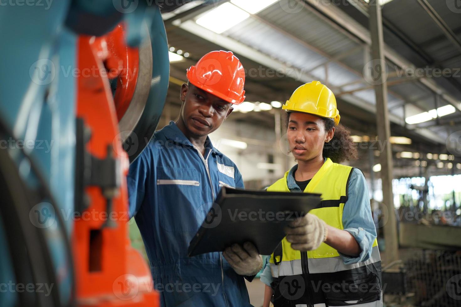 wartungsingenieure arbeiten vor der automatisierten reparatur von cnc-maschinen an einer wartungscheckliste an der produktionslinie. foto