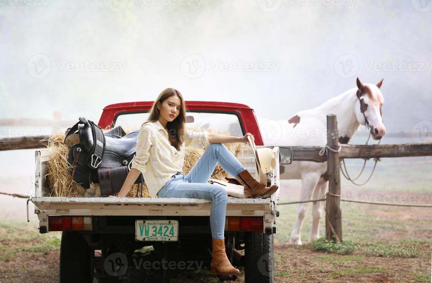 Cowgirl-Model posiert auf dem Bauernhof. ein Porträt eines schönen jungen Cowgirls, das sich in einem Stall auf einer Farm an eine Wand lehnt. foto