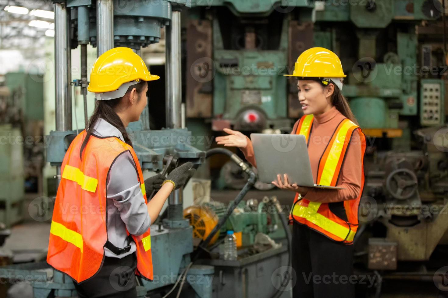 Zwei Arbeiterinnen arbeiten auf dem Werksgelände und überprüfen die Maschine in der Produktlinie oder die Produkte vor Ort. ingenieur oder techniker, der material oder maschine in der anlage überprüft. Industrie und Fabrik. foto