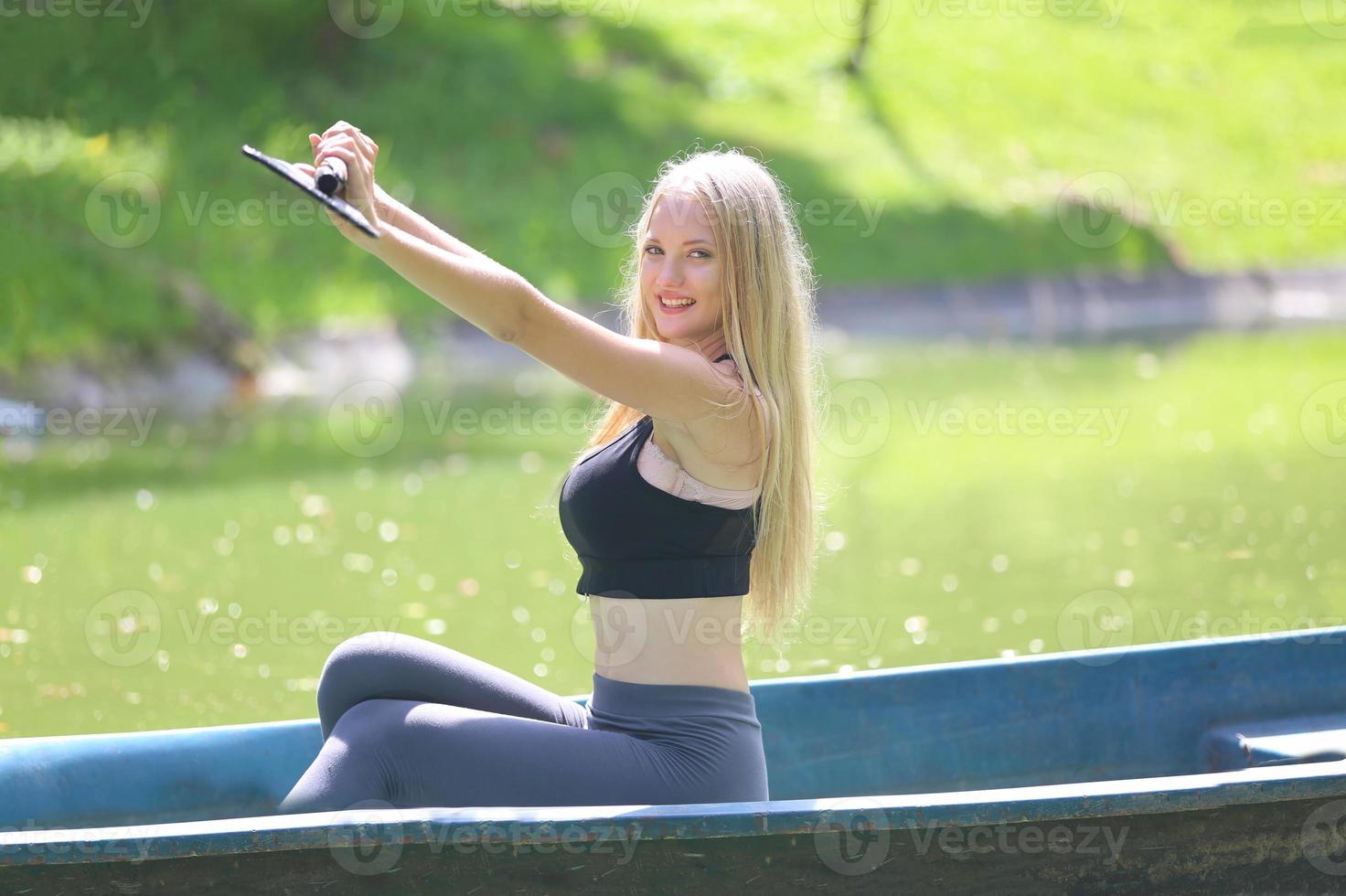 Eine schöne Frau in Turnkleidung sitzt in einem Boot und genießt tagsüber die Natur im Garten. foto