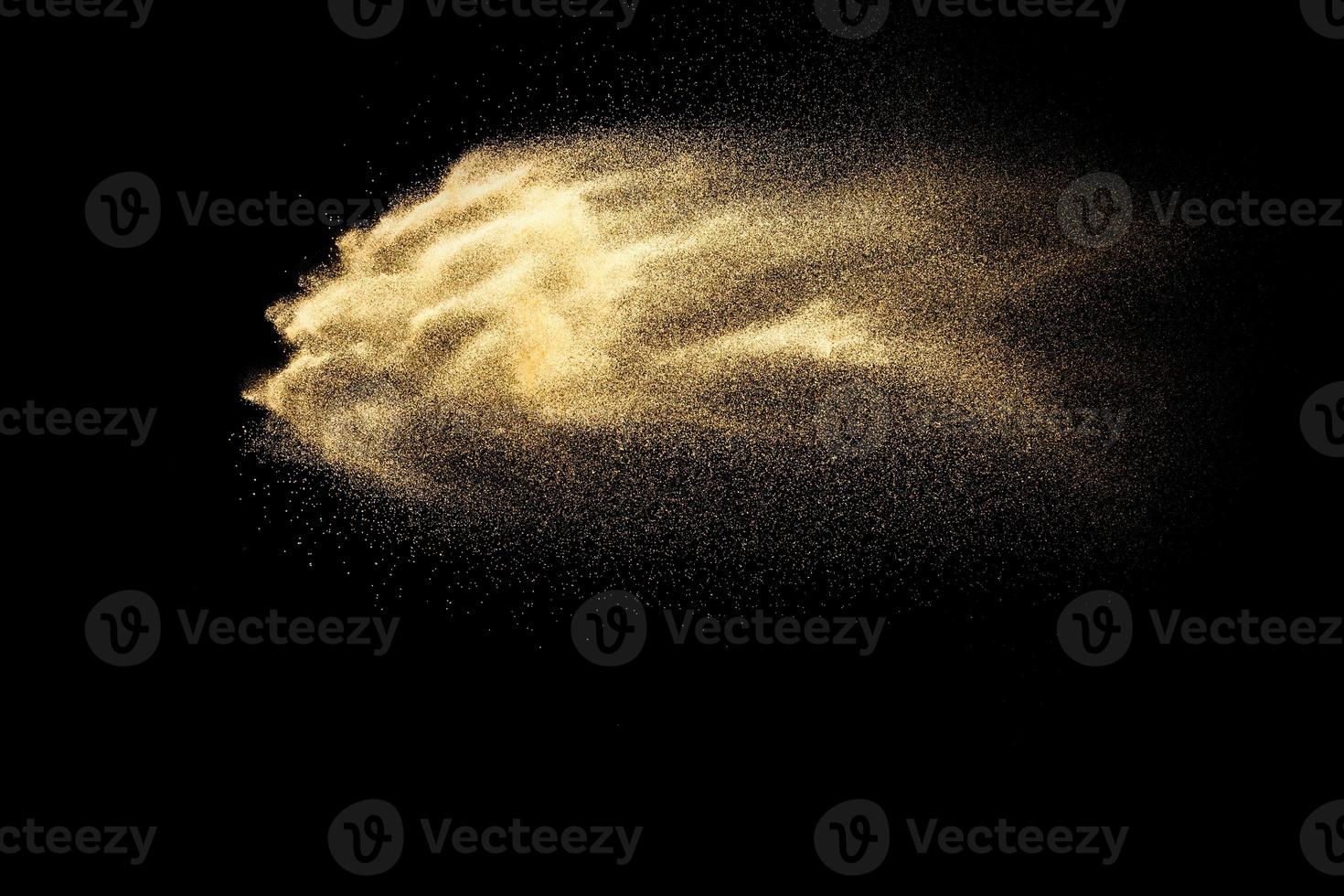 abstrakte sandwolke.goldener sandspritzer vor dunklem hintergrund.gelbe sandfliegenwelle in der luft. Sand explodiert auf schwarzem Hintergrund und wirft Freeze-Stop-Motion-Konzept. foto