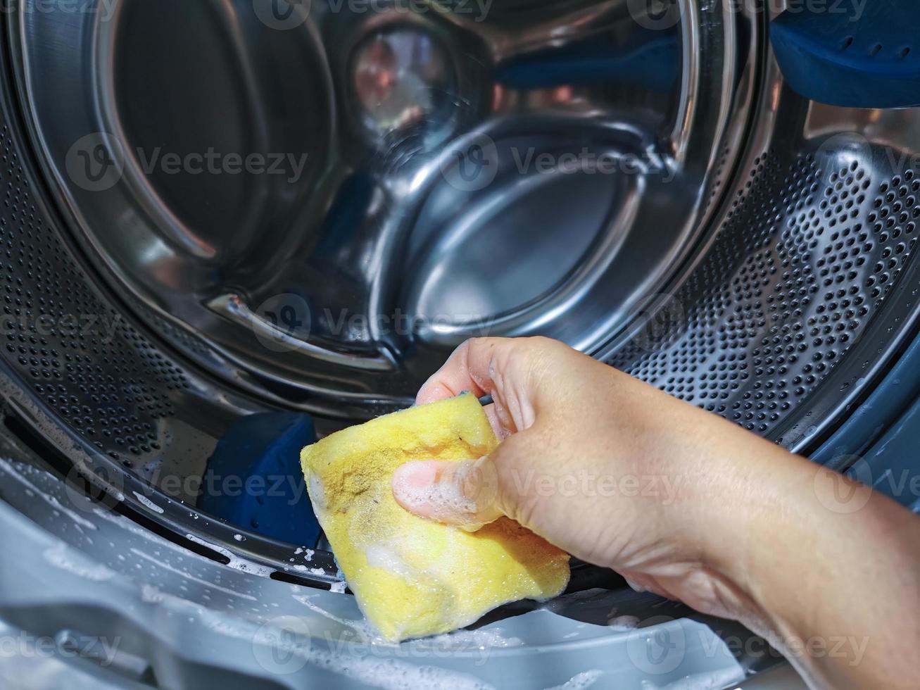 close up hand verwenden sie den schwamm zur reinigung in der frontlader-waschmaschine der waschtrommel. foto