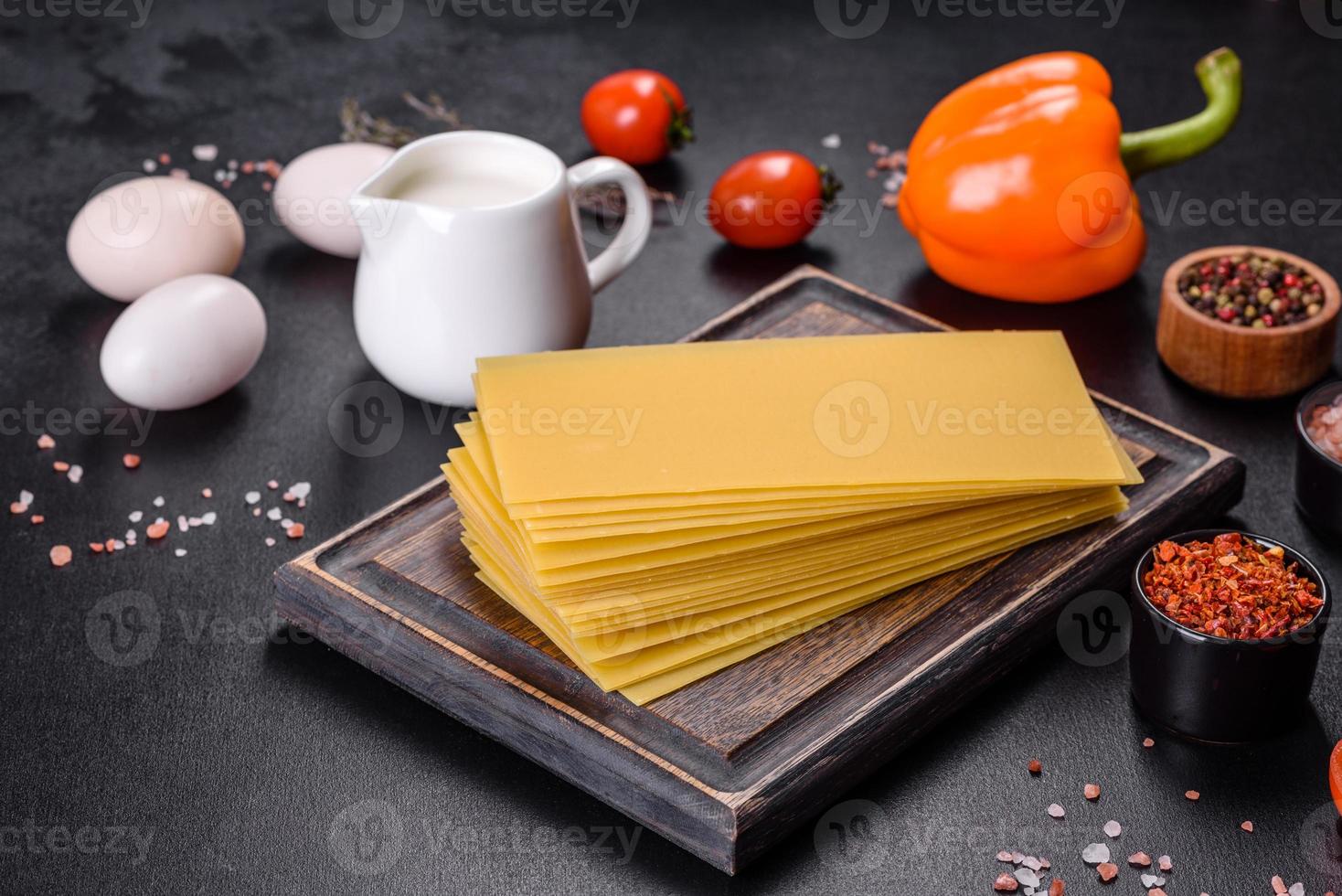 Stapel von Lasagneplatten auf dunklem Betonhintergrund. Zutaten für Lasagne foto