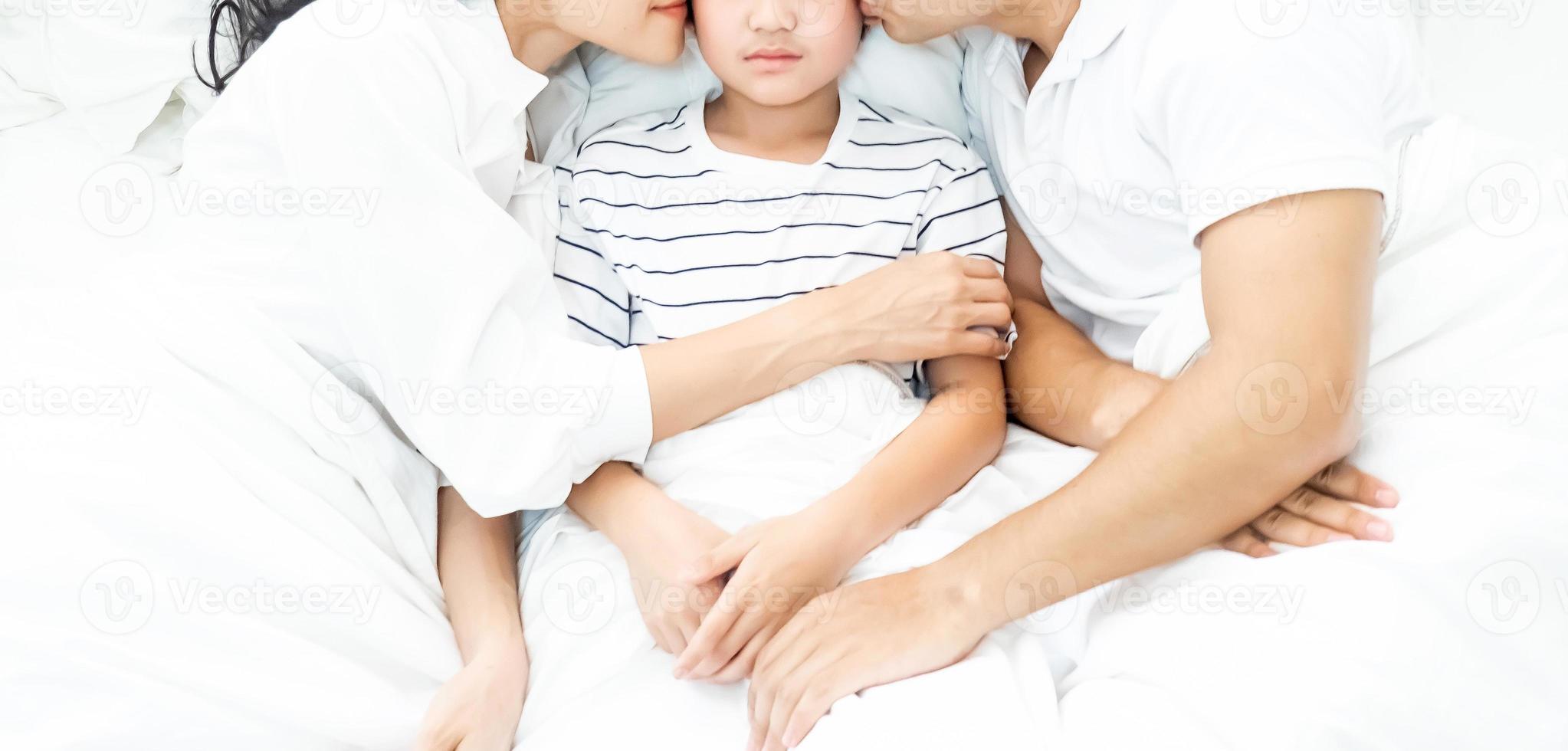 Vater, Mutter und Kind liegen im Bett foto