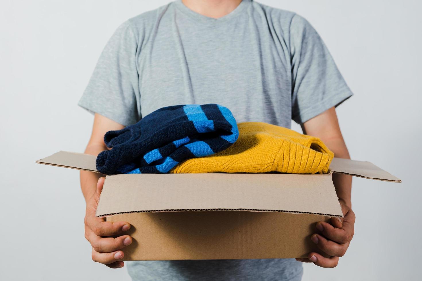 Mann hält eine Kiste mit Second-Hand-Kleidung unbenutzte Kleidung foto