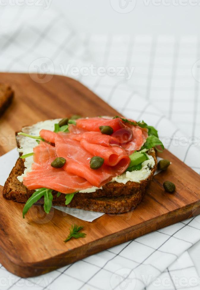 Räucherlachs-Sandwich mit Käse, Pistazien und Blattsalaten, Schwarzbrot foto