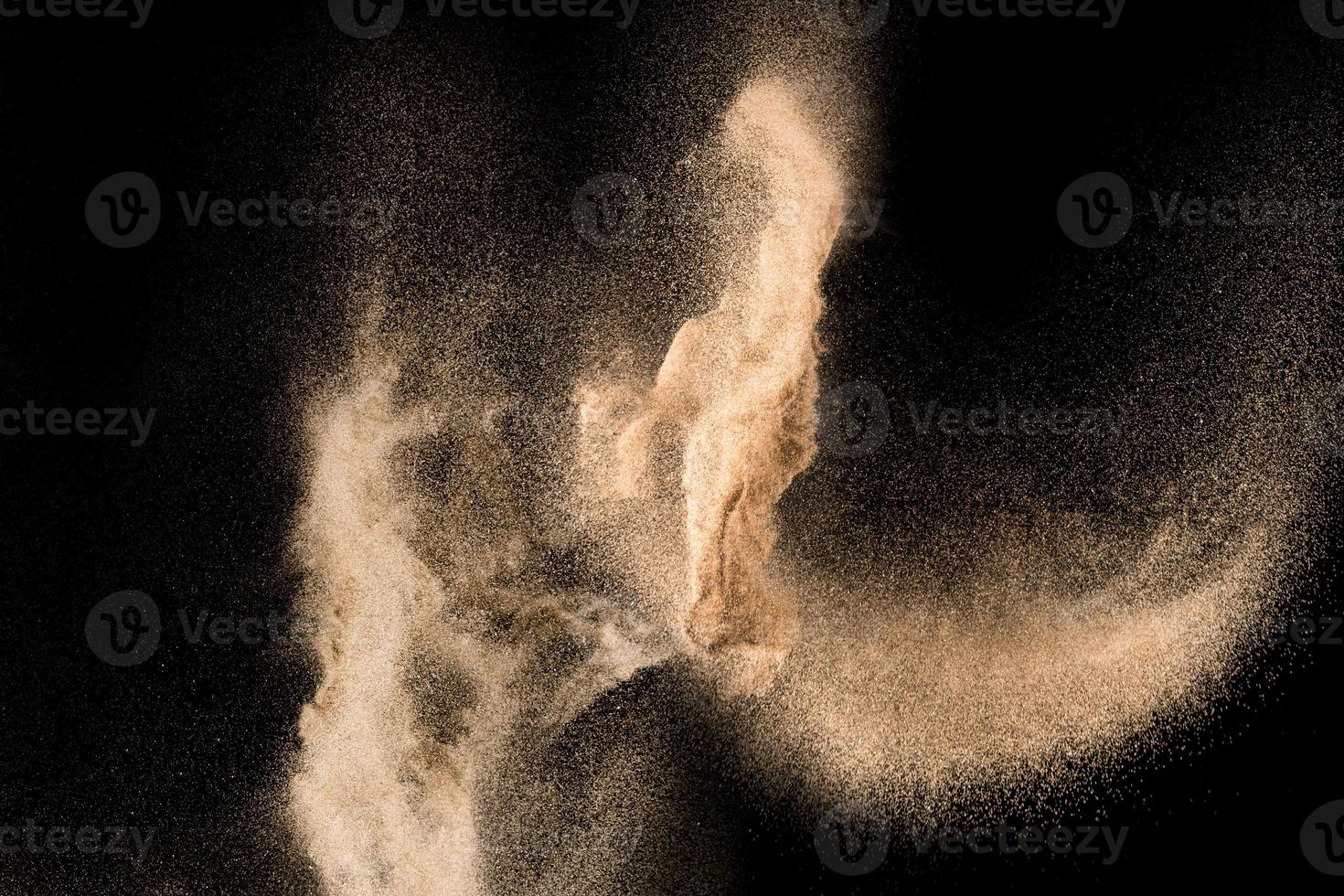 trockene Flusssandexplosion. goldfarbener Sandspritzer vor schwarzem Hintergrund. foto