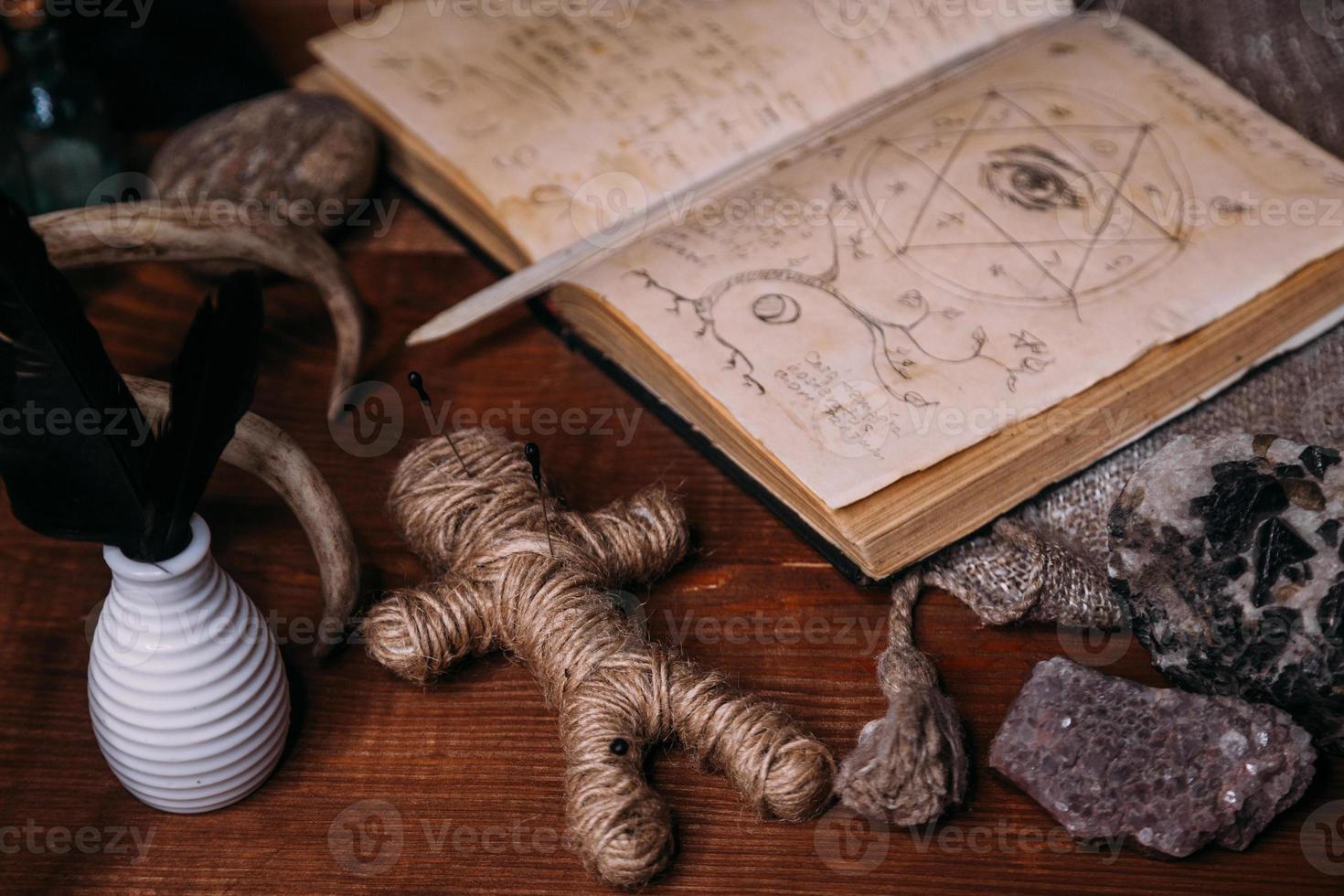 eine voodoo-puppe aus seil liegt mit altem buch grimoire foto