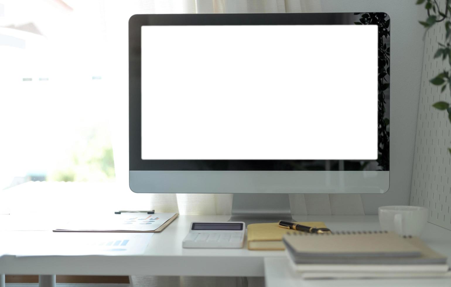 Desktop-Computer mit leerem Bildschirm in minimalem Büroraum mit Dekorationen und Kopierfläche foto