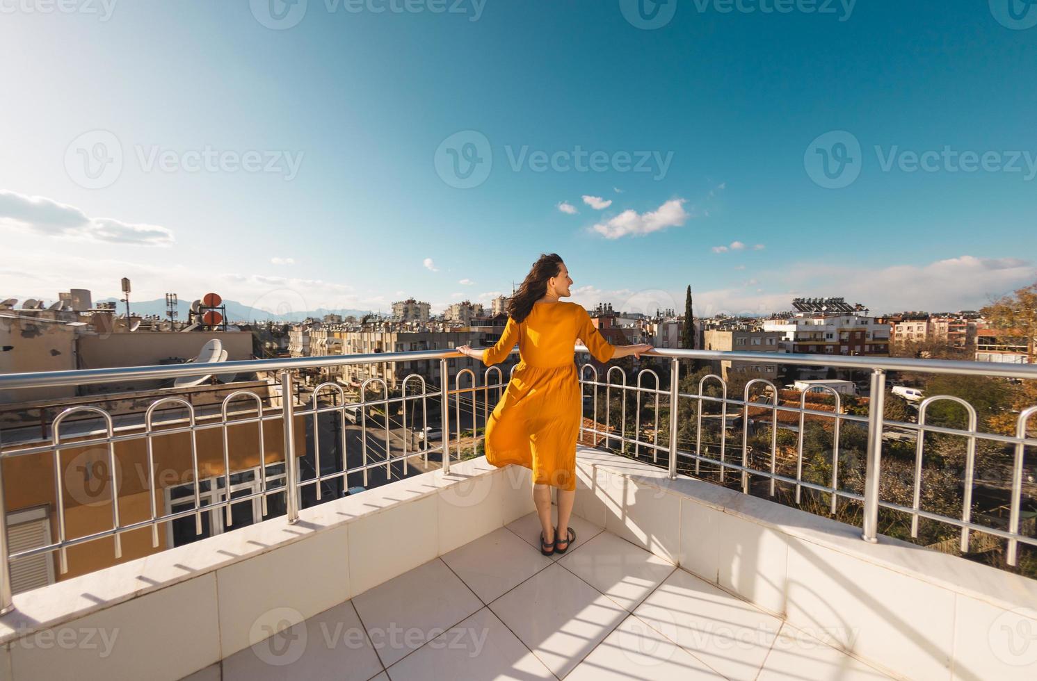 Ein attraktives Mädchen blickt auf die Stadt und der Wind bläst ihr Kleid auf foto