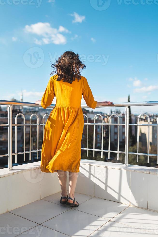 Ein attraktives Mädchen blickt auf die Stadt und der Wind bläst ihr Kleid auf foto