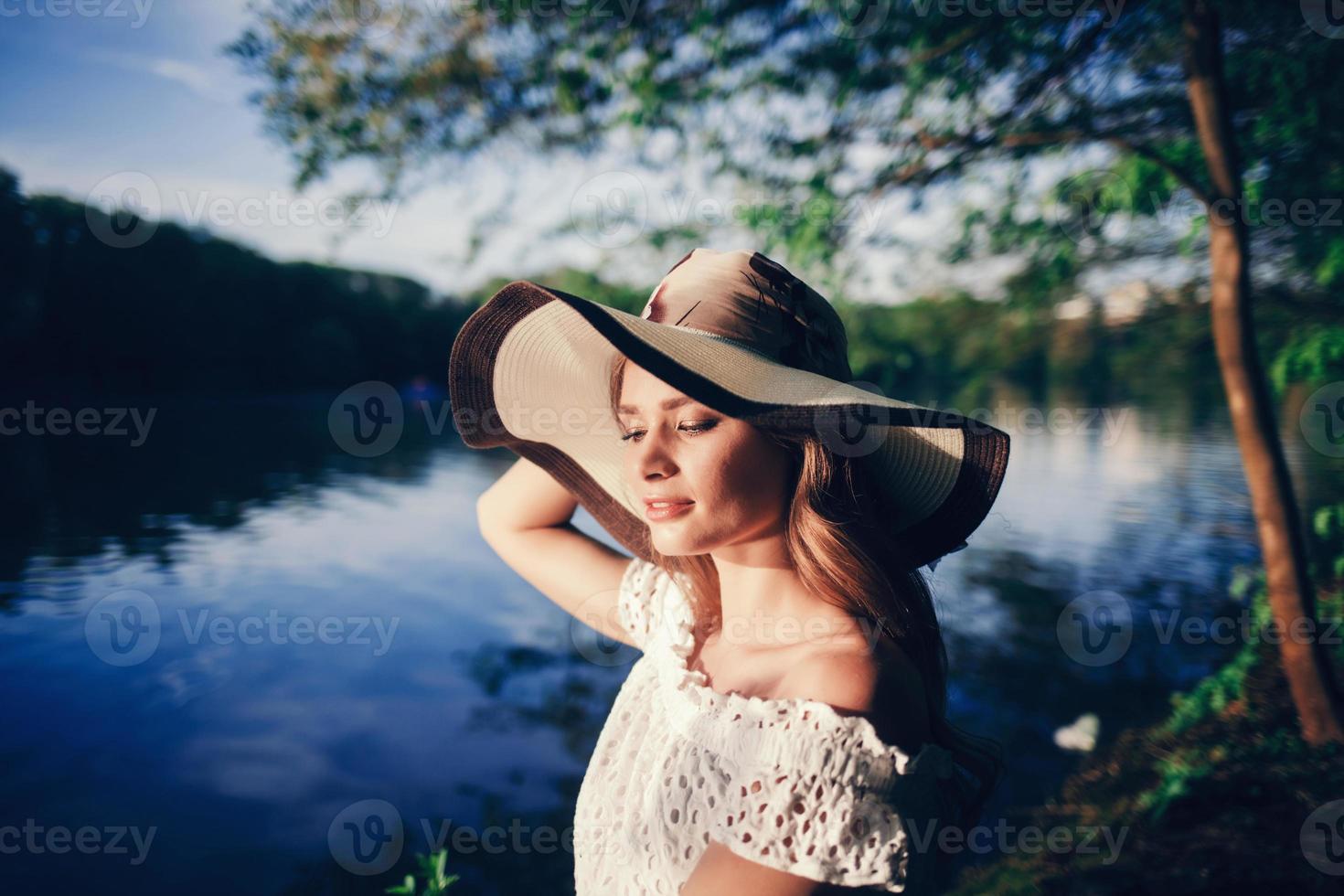 Porträt eines charmanten Mädchens mit Hut und weißem Kleid foto