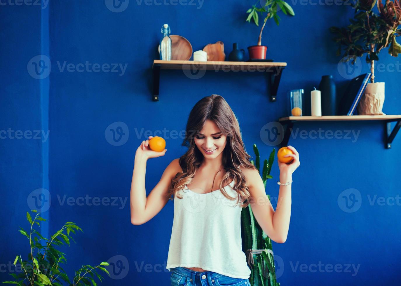 Frau auf leuchtend blauem Hintergrund hält Orange foto