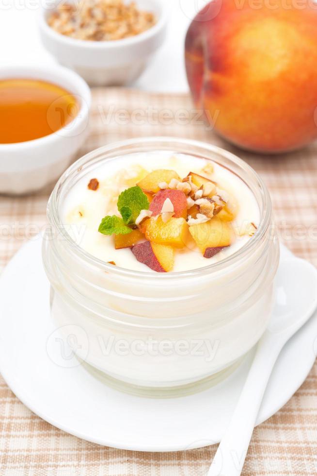 hausgemachter Joghurt mit Honig, Pfirsichen und Nüssen, vertikal foto