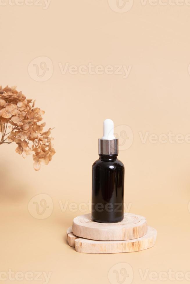 Holzpodium oder Sockel mit einer Tropfflasche mit Kosmetiköl oder Serum. neutrales beige monochromes hautpflegekonzept foto