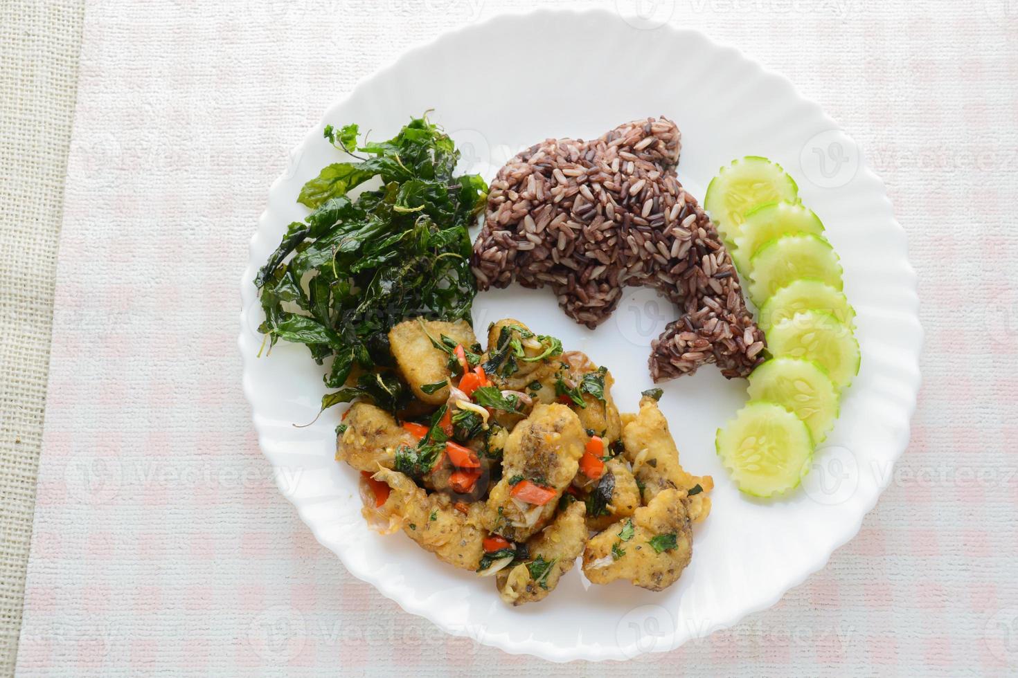 gebratener Fisch mit Chili und Basilikum, serviert mit gedämpftem Reis und Gurken, scharfes und würziges Gericht. foto