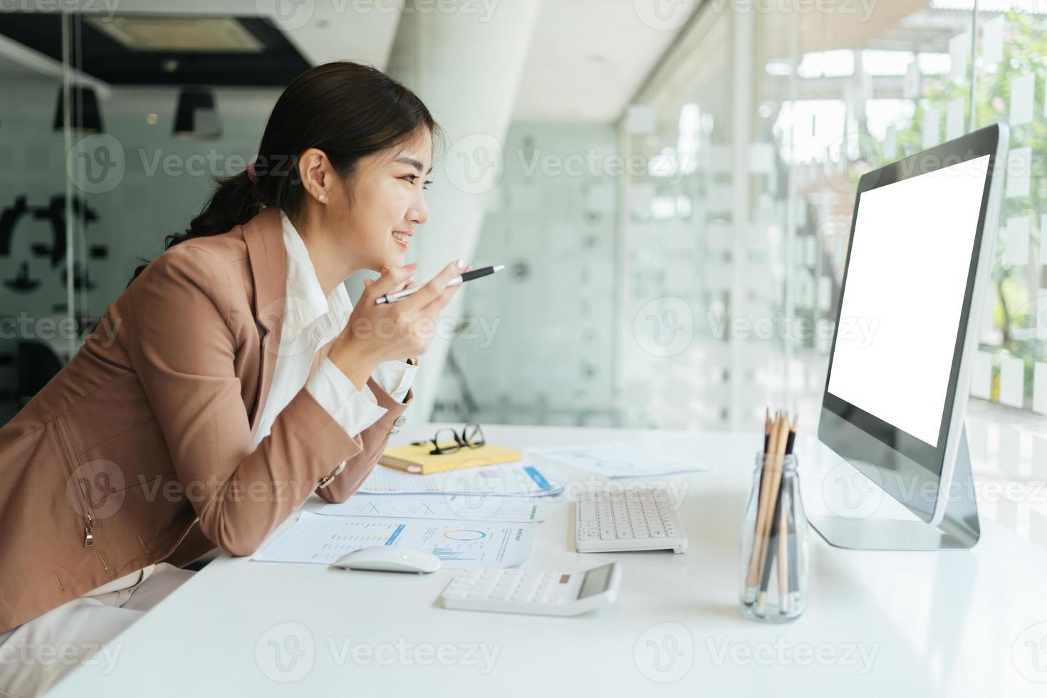 glückliche attraktive asiatische geschäftsfrau, die mit einem laptop und einem finanzdokument im büro arbeitet, erfolgreiche aktion, geschäftskonzept. foto