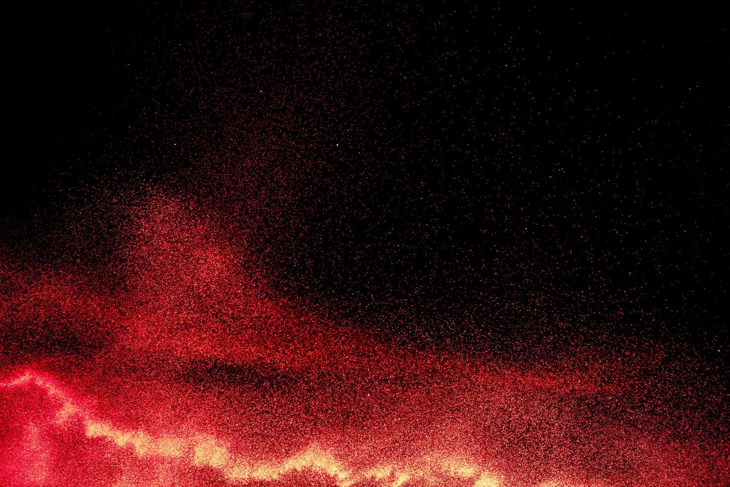 rote Pulverexplosion auf schwarzem Hintergrund. bewegung von roten staubpartikeln spritzen einfrieren. foto
